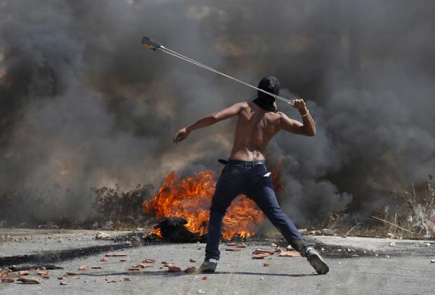A Palestinian protester uses a sling to hurl stones towards Israeli troops during clashes near the Jewish settlement of Bet El, near the occupied West Bank city of Ramallah, October 5, 2015. REUTERS/Mohamad Torokman